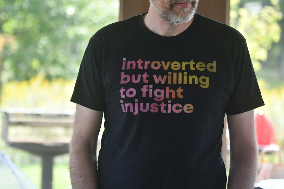 Man wears t-shirt with "introverted but willing to fight injustice".